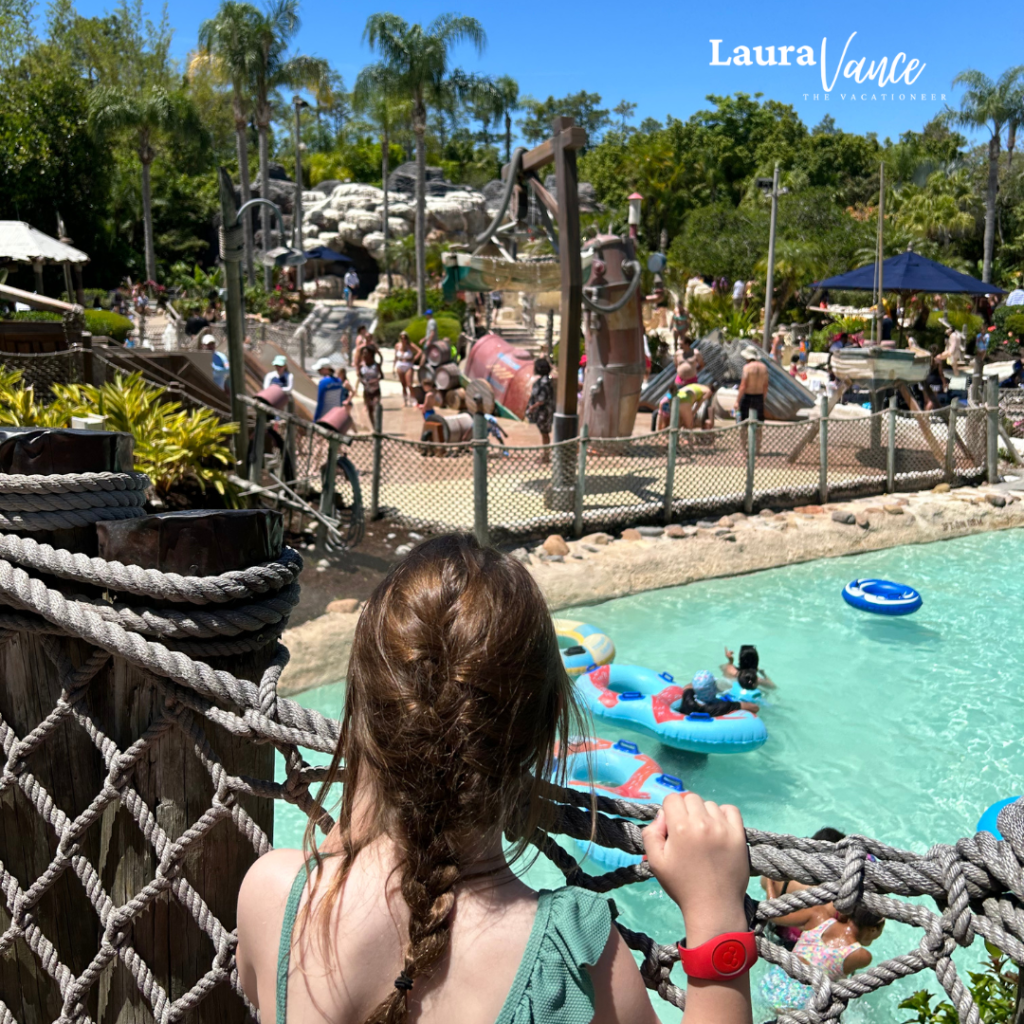 A girl stands on a bridge overlooking the lazy river at Typhoon Lagoon—one of the top ways to stay cool at Disney World in the summer heat.
